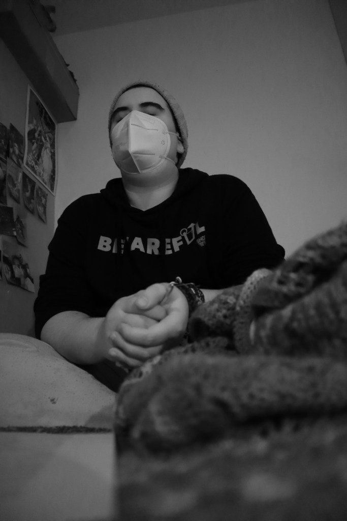 A black and white photo of Aspen holding a crochet hook, eyes closed.