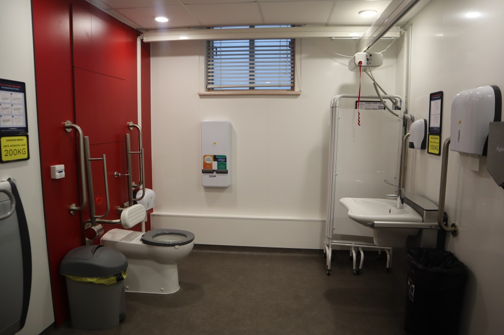 A fully equipped changing places toilet, with a hoist, height-adjustable sink and adult changing table.
